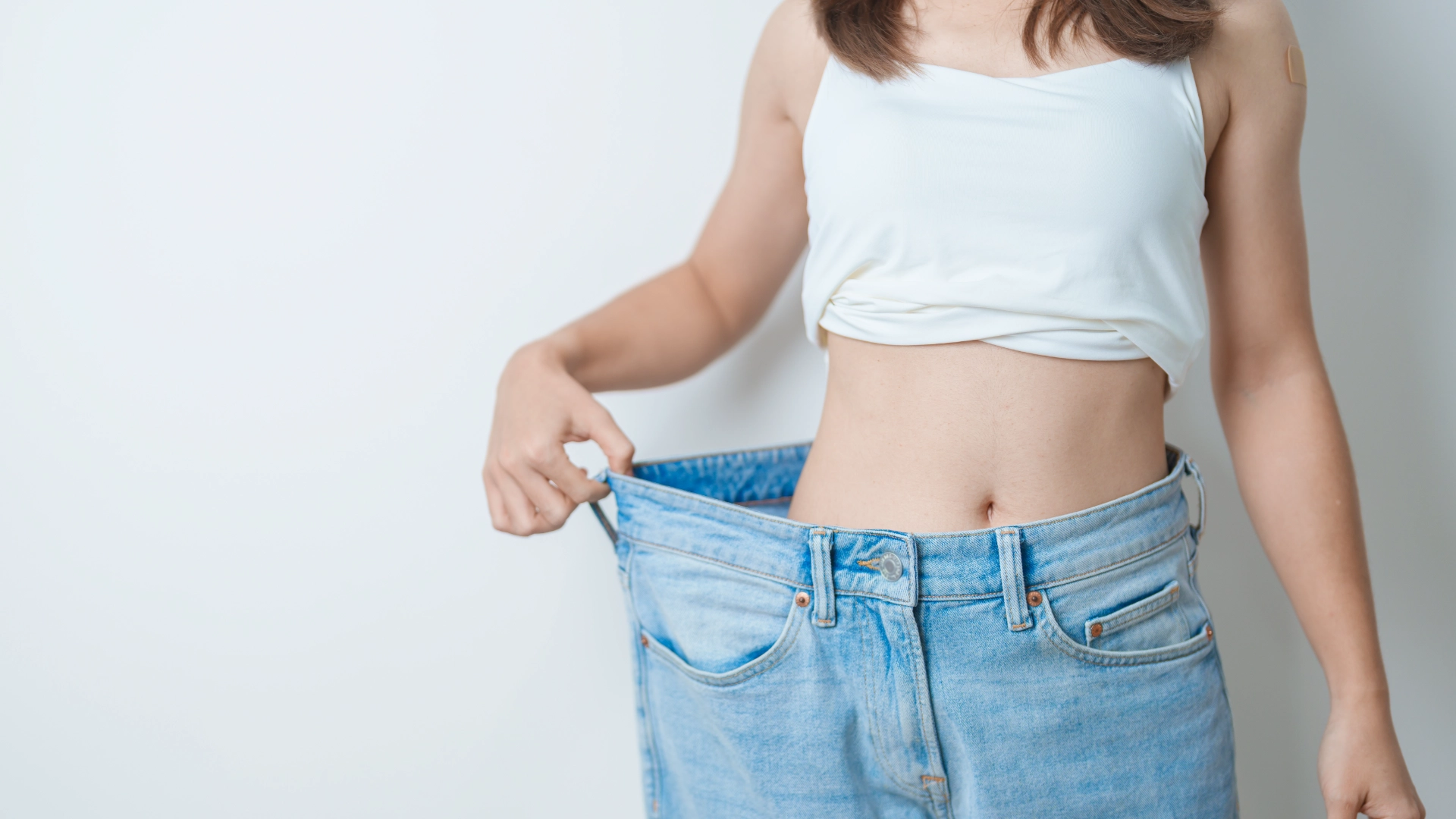 Person showing loose-fitting jeans waist.